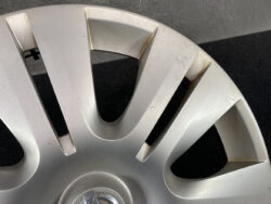 Close-up of a silver car wheel cover with scratches and scuff marks along the spokes.