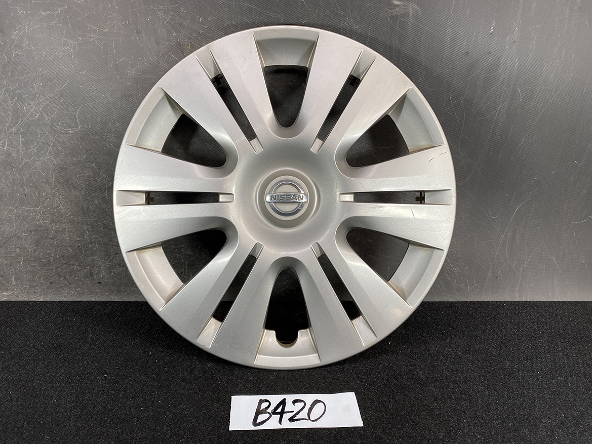 B420_1 NISSAN Genuine 15inch WHEEL CAP / HUB CAP 40315-1GK0A x1 » NZ.95 » JDM-PARTS NZ » JDM-PARTS NZ Front view of a silver Nissan hubcap with multiple angled spokes and a central Nissan emblem, placed on a dark surface with a handwritten 'B420' label beneath. NISSAN Genuine 15inch WHEEL CAP / HUB CAP 40315-1GK0A x1 » JDM-PARTS NZ