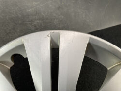 Close-up of a silver alloy wheel rim with a visible scratch between two spokes.