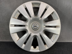 Silver Nissan hubcap with circular center emblem and 12 spokes, showing light wear and rust at inner edges, used wheel cover sample.