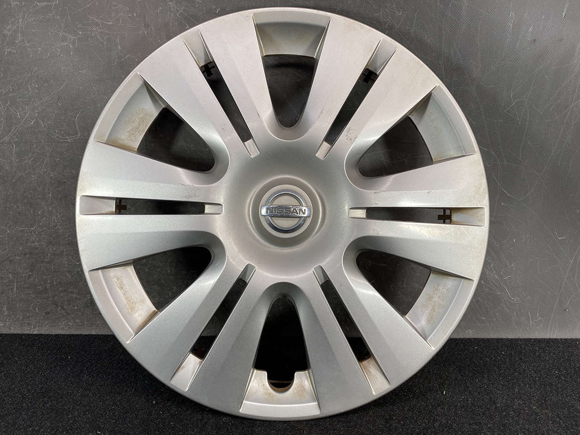 B421_2 NISSAN Genuine 15inch WHEEL CAP / HUB CAP 40315-1GK0A x1 » NZ.95 » JDM-PARTS NZ » JDM-PARTS NZ Silver Nissan hubcap with circular center emblem and 12 spokes, showing light wear and rust at inner edges, used wheel cover sample. NISSAN Genuine 15inch WHEEL CAP / HUB CAP 40315-1GK0A x1 » JDM-PARTS NZ