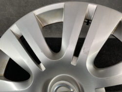 Close-up of a silver alloy wheel hubcap with scratches and scuff marks across the surface