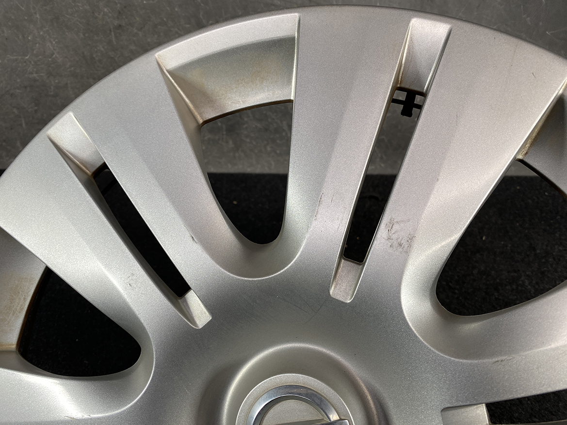 B421_5 NISSAN Genuine 15inch WHEEL CAP / HUB CAP 40315-1GK0A x1 » NZ.95 » JDM-PARTS NZ » JDM-PARTS NZ Close-up of a silver alloy wheel hubcap with scratches and scuff marks across the surface NISSAN Genuine 15inch WHEEL CAP / HUB CAP 40315-1GK0A x1 » JDM-PARTS NZ