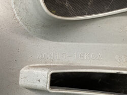 Close-up of a silver metal surface with the stamped code 40315-1GK0A on it, near a recessed opening.
