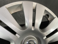 Close-up of a silver alloy wheel hubcap with visible scratches and scuffs on several spokes and around the center cap area.