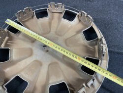 Brown plastic car wheel cover with rectangular openings; tape measure laid across shows about 40 cm diameter.