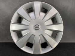 Silver Nissan wheel hubcap with a central Nissan emblem and bold, angular spokes radiating outward.