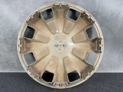 Back side of a beige plastic wheel hubcap with eight rectangular openings and edge mounting clips.