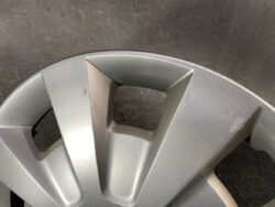 Close-up of a silver car wheel hubcap with angular spokes and a square central cutout