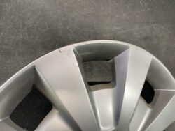 Close-up of a silver car wheel hubcap with geometric spokes and minor scratches on the rim edge.