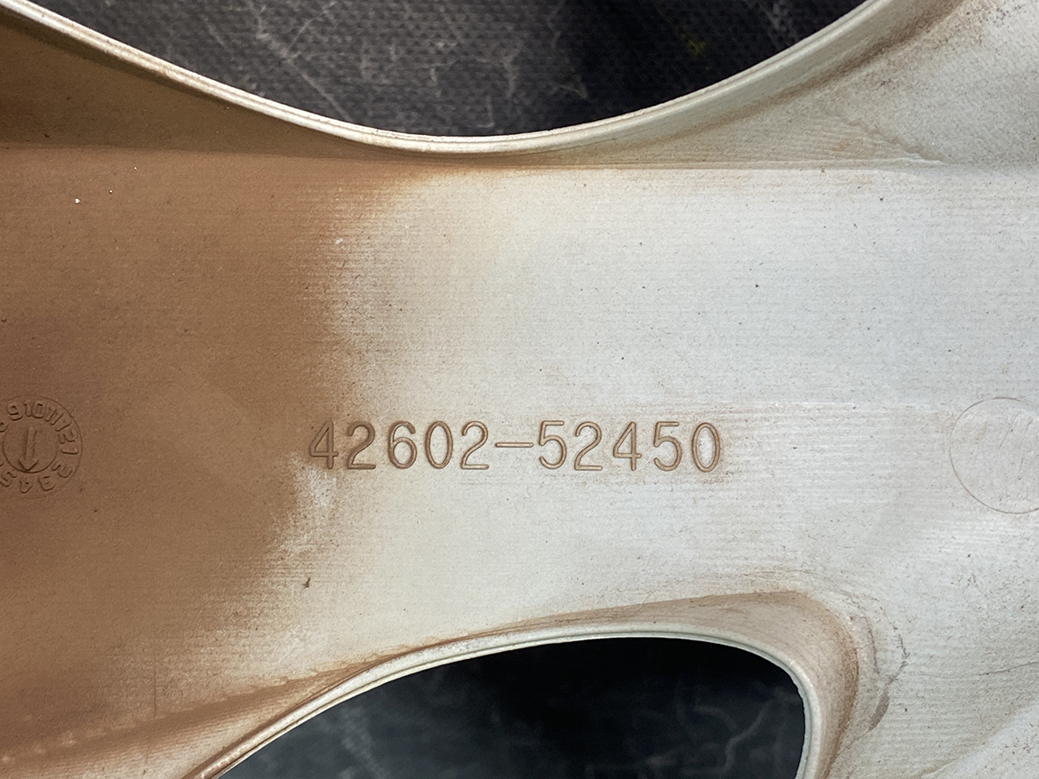 B430_4 TOYOTA PORTE / SPADE Genuine 15inch WHEEL CAP / HUB CAP 42602-52450 x1 » NZ.95 » JDM-PARTS NZ » JDM-PARTS NZ Close-up of a brushed metal surface with the embossed number 42602-52450 and brown dust on the left side. TOYOTA PORTE / SPADE Genuine 15inch WHEEL CAP / HUB CAP 42602-52450 x1 » JDM-PARTS NZ