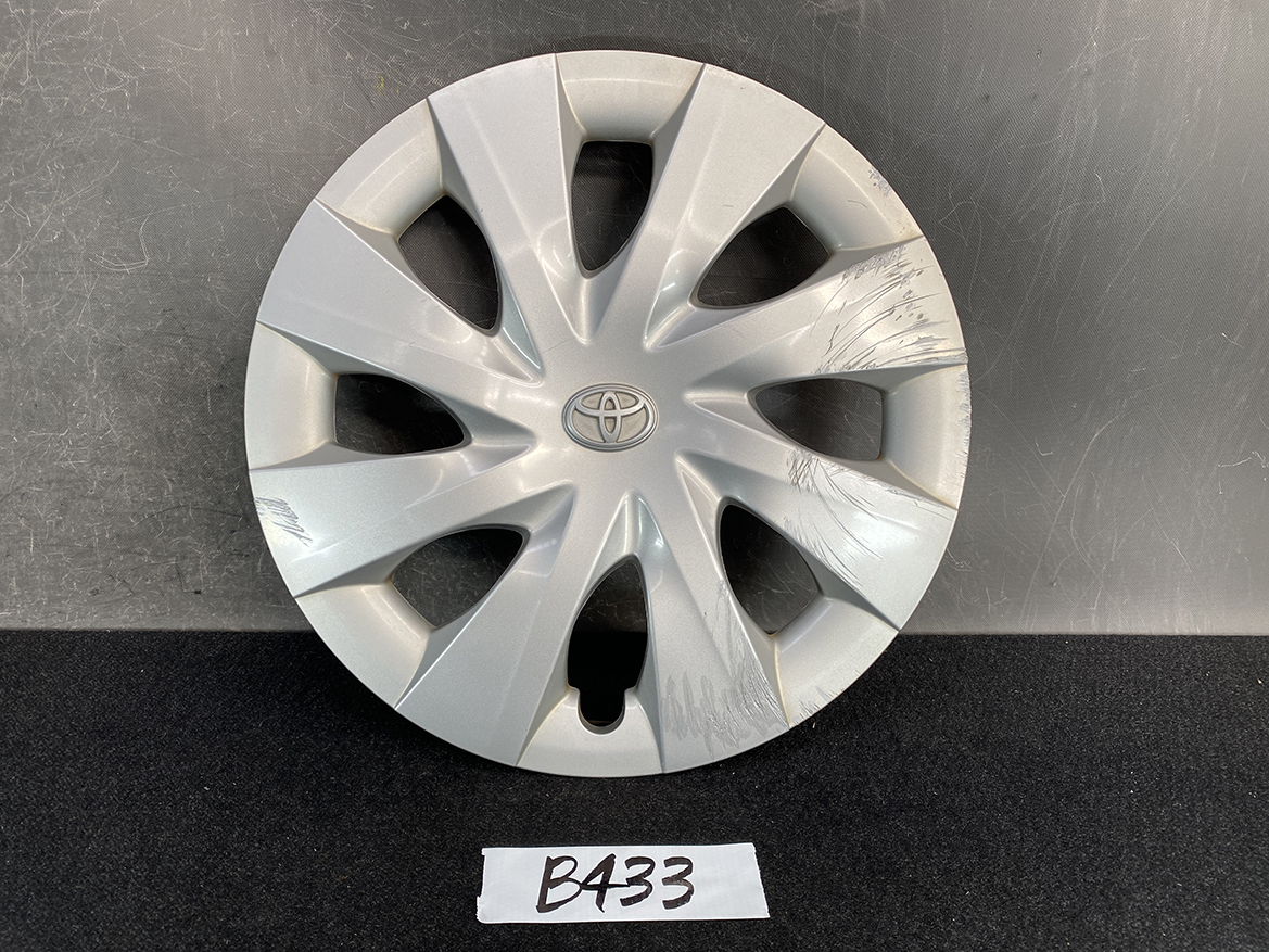 B433_1 TOYOTA PORTE / SPADE Genuine 15inch WHEEL CAP / HUB CAP 42602-52450 x1 » NZ.95 » JDM-PARTS NZ » JDM-PARTS NZ Silver Toyota hubcap with a central logo and several scratches on the right side, resting on a dark surface. TOYOTA PORTE / SPADE Genuine 15inch WHEEL CAP / HUB CAP 42602-52450 x1 » JDM-PARTS NZ