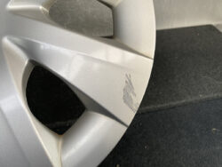 Close-up of a silver alloy wheel with a scratch along the rim edge, showing brushed damage on the surface.