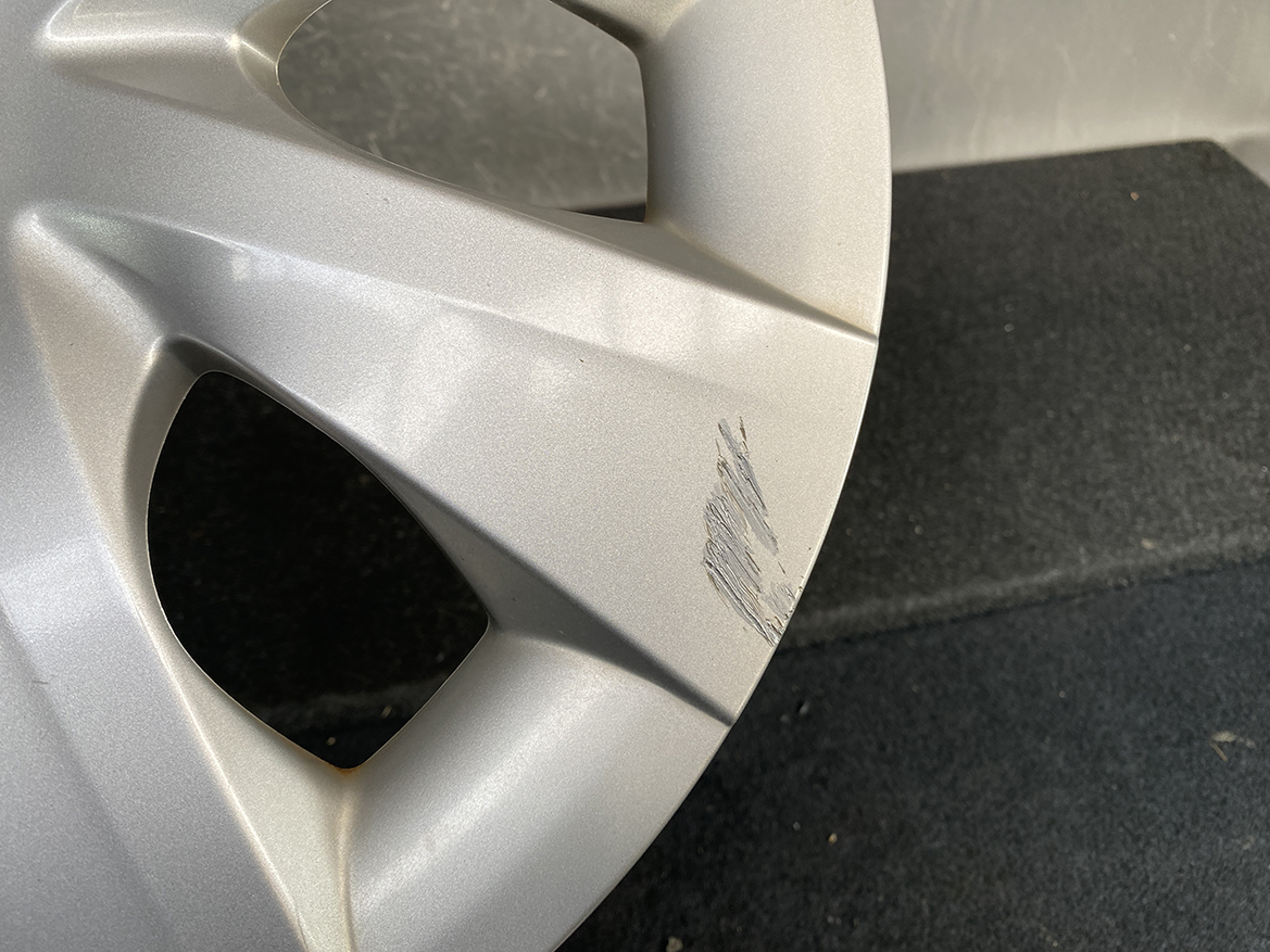 B433_5 TOYOTA PORTE / SPADE Genuine 15inch WHEEL CAP / HUB CAP 42602-52450 x1 » NZ.95 » JDM-PARTS NZ » JDM-PARTS NZ Close-up of a silver alloy wheel with a scratch along the rim edge, showing brushed damage on the surface. TOYOTA PORTE / SPADE Genuine 15inch WHEEL CAP / HUB CAP 42602-52450 x1 » JDM-PARTS NZ