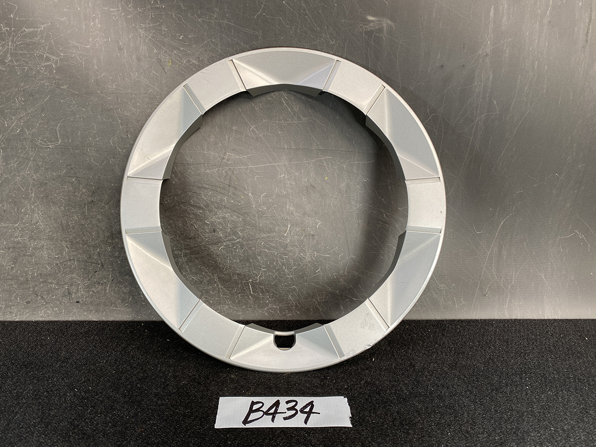 B434_1 TOYOTA PRIUS NHW20 Genuine 15inch WHEEL CAP / HUB CAP x1 » NZ.95 » JDM-PARTS NZ » JDM-PARTS NZ Gray circular ring with faceted outer edge and a small notch at the bottom, placed on a dark surface. TOYOTA PRIUS NHW20 Genuine 15inch WHEEL CAP / HUB CAP x1 » JDM-PARTS NZ