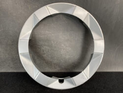 Circular gray ring with a segmented outer edge resting on a dark surface.