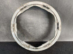 Circular gray plastic frame with inner rails and small latches, resting on a dark textured surface.