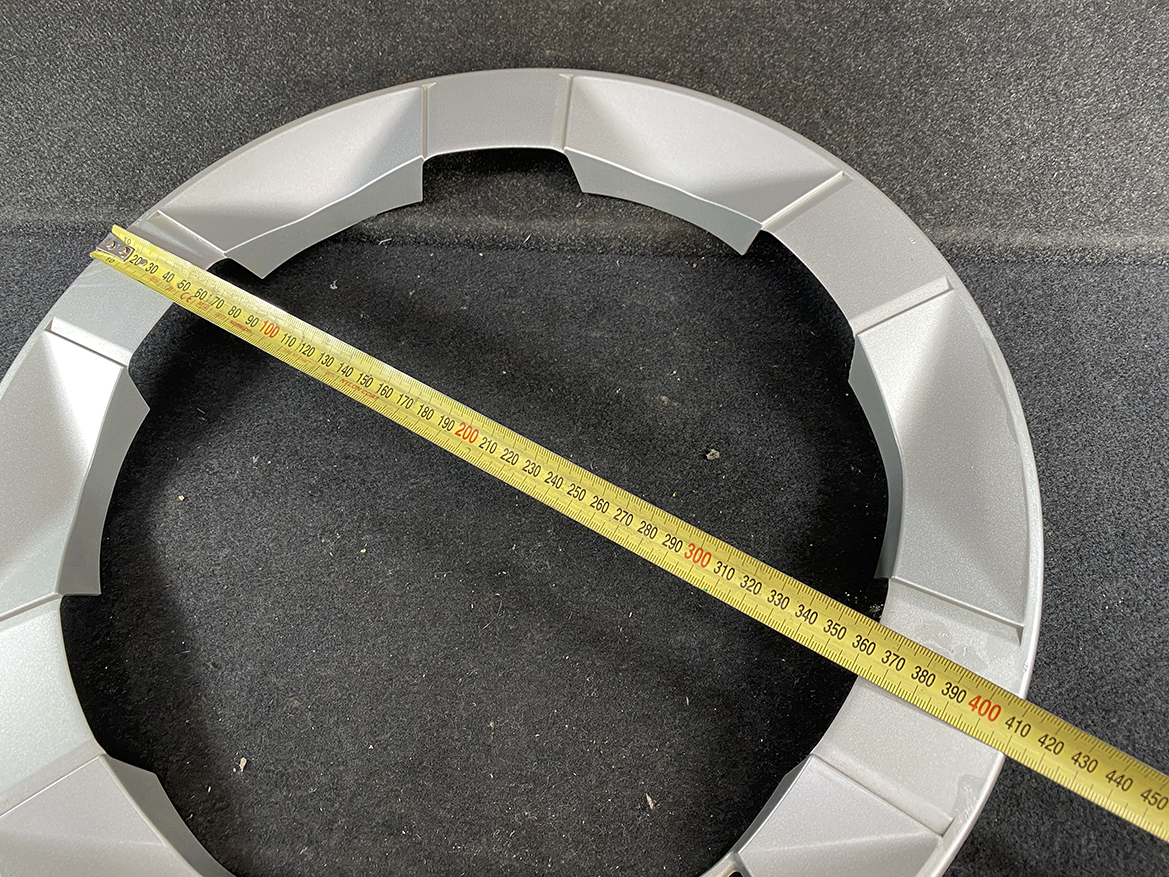 B434_4 TOYOTA PRIUS NHW20 Genuine 15inch WHEEL CAP / HUB CAP x1 » NZ.95 » JDM-PARTS NZ » JDM-PARTS NZ Gray circular modular frame on a dark carpet with a yellow measuring tape laid diagonally across it, showing a measurement span. TOYOTA PRIUS NHW20 Genuine 15inch WHEEL CAP / HUB CAP x1 » JDM-PARTS NZ