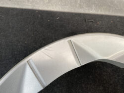 Close-up of a light gray curved plastic surface with a few scratches and a vertical seam line.