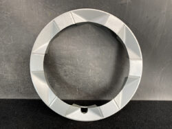 Gray circular ring with segmented outer edge resting on a scratched dark work surface.