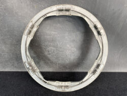Circular gray plastic ring with embedded metal rails, placed on a scratched dark surface.