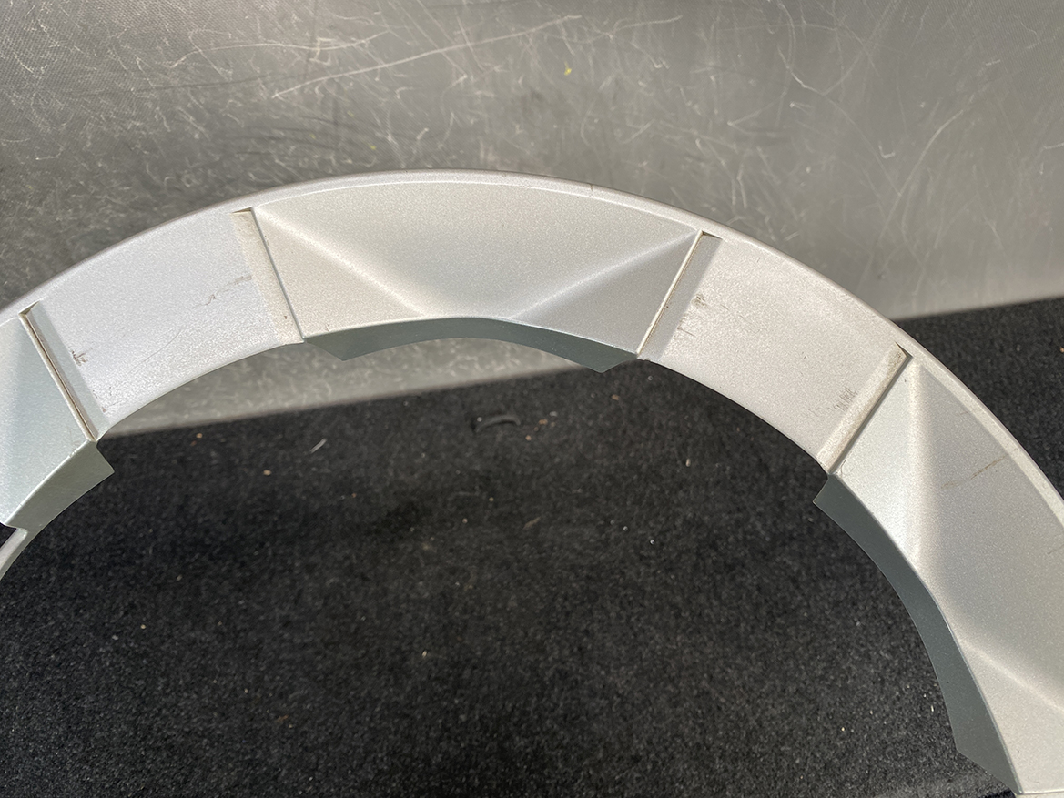 B435_4 TOYOTA PRIUS NHW20 Genuine 15inch WHEEL CAP / HUB CAP x1 » NZ.95 » JDM-PARTS NZ » JDM-PARTS NZ Close-up of a light-gray segmented circular frame with angular, pyramid-like panels on a dark surface. TOYOTA PRIUS NHW20 Genuine 15inch WHEEL CAP / HUB CAP x1 » JDM-PARTS NZ