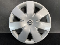 Silver Nissan hubcap with a six-spoke design and visible scratches around the edge, center logo in focus