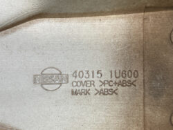 Nissan part stamp on beige plastic showing part number 40315 1U600 and material: cover PC+ABS (ABS).
