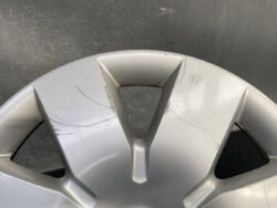 Close-up of a silver car alloy wheel hubcap with multiple scratch marks around the center hole.