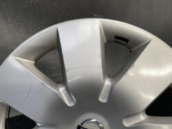Close-up of a silver alloy wheel cover with multiple scratches and scuffs.