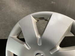 Close-up of a silver car wheel cover with triangular spokes and visible scratches/scuffs.