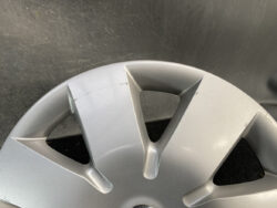 Close-up of a silver alloy wheel with visible scratches and scuffs against a dark background