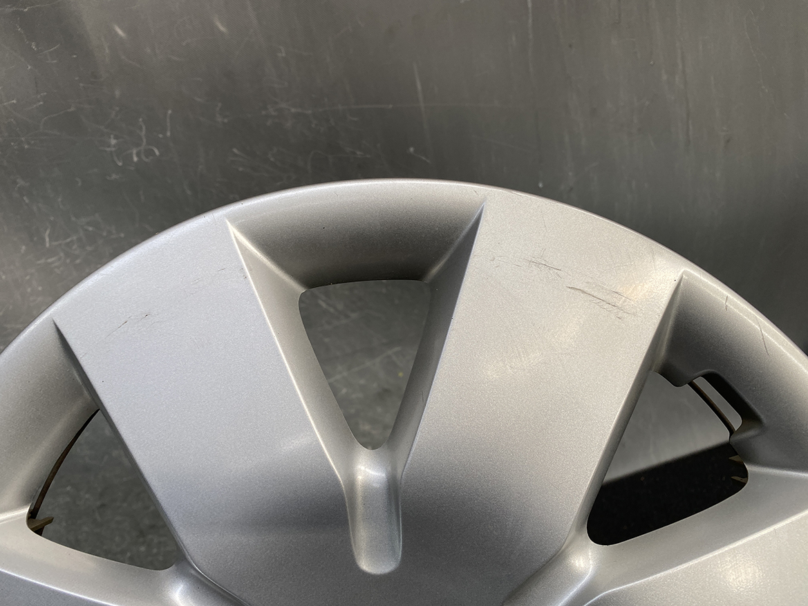 B440_6 NISSAN NOTE E11 Genuine 14inch WHEEL CAP / HUB CAP x1 40315 1U600 x1 » NZ.95 » JDM-PARTS NZ » JDM-PARTS NZ Close-up of a silver plastic car wheel hubcap with visible scratches and scuff marks. NISSAN NOTE E11 Genuine 14inch WHEEL CAP / HUB CAP x1 40315 1U600 x1 » JDM-PARTS NZ