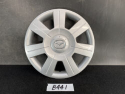 Silver Mazda hubcap with eight spokes and central Mazda logo on a dark surface.