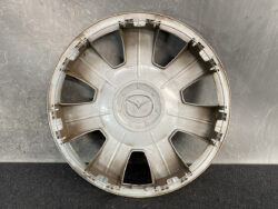 Grey plastic car hubcap with eight spokes, lying on a dark surface.