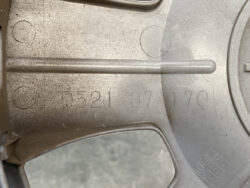 Close-up of a dusty gray mechanical housing with stamped code: D521 37 170, and a horizontal rod protruding across the middle.