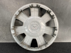 Circular silver car wheel hubcap with eight wide spokes and a central cap, showing edge clips for mounting on a wheel