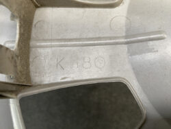 Close-up of a gray metal component with the stamped code K6805 and circular markings on the surface.