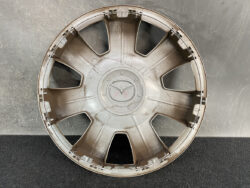 Plastic car wheel hubcap with eight spokes and central cap, dusty beige color and visible attachment clips around the rim