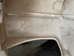 Close-up of dusty metal surface with stamped code K6805 and circular indent marks.