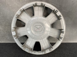 Circular silver car wheel hubcap with six spokes and a central cap, showing a slightly dusty surface.