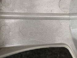 Close-up of a dull silver alloy wheel surface with the stamped identifier K6805 intact on the metal edge.