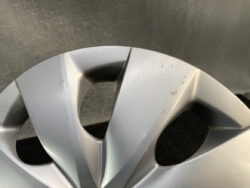 Close-up of a silver car alloy wheel with light surface scratches and dirt.