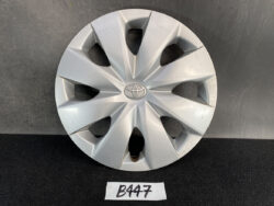 Silver Toyota hubcap with an eight-spoke star design and central logo on a dark surface, labeled 'B447' nearby.