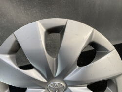 Close-up of a silver Toyota hubcap with scratches and scuff marks on the surface.