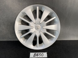 Silver Toyota hubcap wheel cover with a multi-spoke design on a dark surface