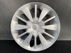 Silver Toyota hubcap with a multi-spoke design and centered Toyota emblem, laid flat on a dark surface.