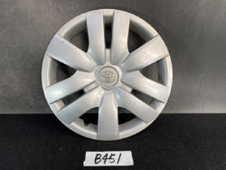 Silver Toyota hubcap (wheel cover) with logo in the center, resting on a dark surface.