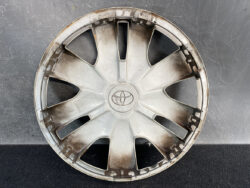 Used Toyota wheel hubcap with dirt and scuff marks, center logo visible