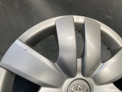 Close-up of a silver Toyota wheel hubcap with a center emblem and minor surface scratches on several spokes.